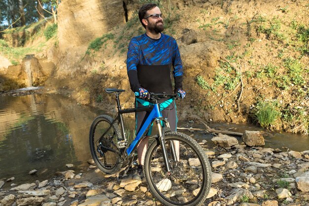 Conquérir les sommets des montagnes par un cycliste en short et maillot sur un vélo semi-rigide moderne en carbone