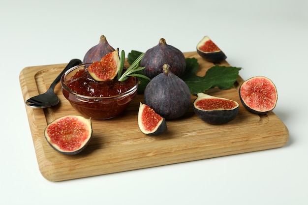 Conseil avec confiture de figues, ingrédients et cuillère sur fond blanc