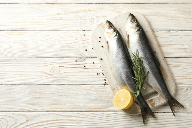 Conseil avec du poisson hareng frais et des épices sur fond de bois blanc