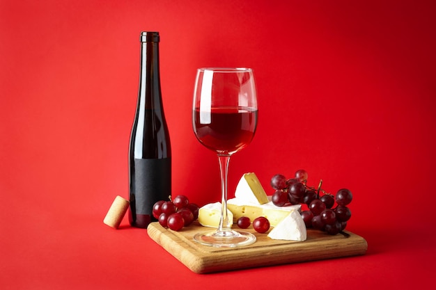 Conseil avec du vin, du fromage et du raisin sur fond rouge