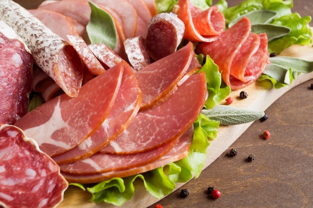 Conseil avec prosciutto, bacon, salami et saucisses sur fond en bois. Coupe froide.