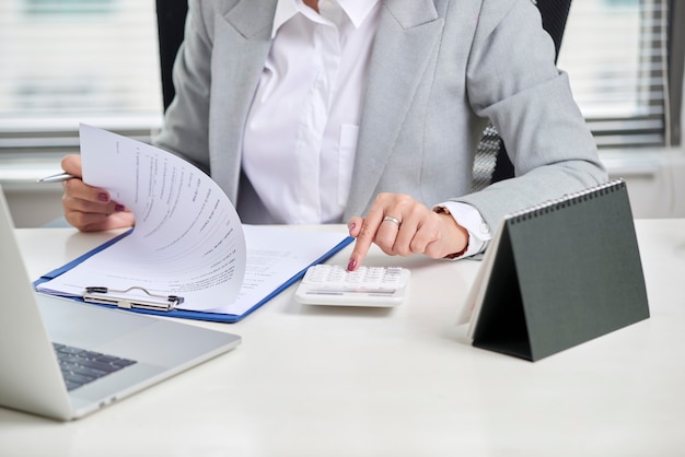 Le conseiller financier à l'aide de la calculatrice examine les états financiers sur le bureau. Concept de comptabilité.