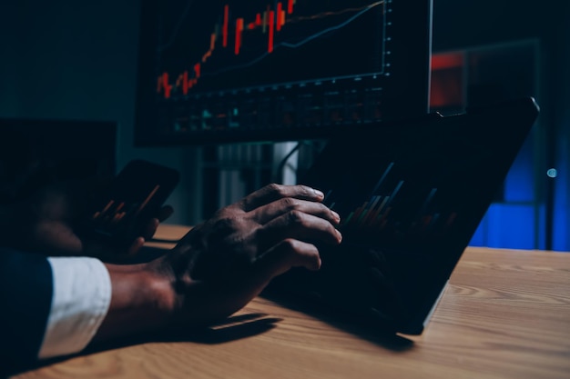 Un conseiller financier, un courtier en actions, de race blanche, à succès, réfléchi et concentré, assis au bureau, regarde l'ordinateur, analyse pensivement les risques et les perspectives d'augmentation ou de chute de la pièce de monnaie crypto-monnaie