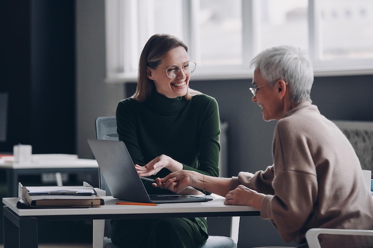Photo un conseiller financier heureux pointant un ordinateur portable tout en discutant d'options avec une femme âgée dans le bureau
