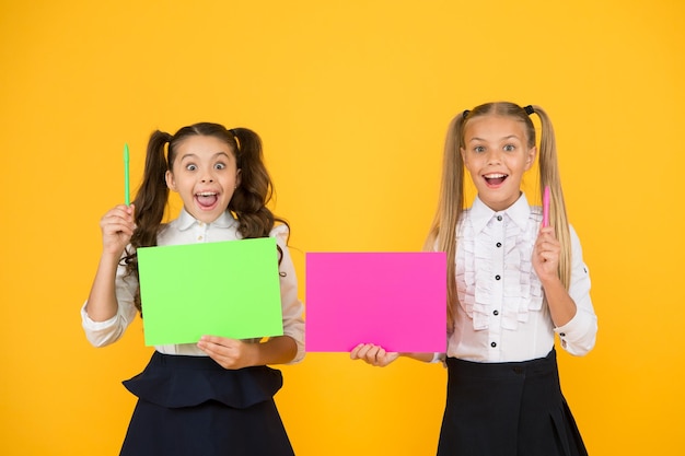 Conseils scolaires de génie Les petits élèves ont des idées Petites filles tenant des stylos et du papier sur fond jaune Petits écoliers avec des notes d'étude Petits enfants créant une présentation pour l'espace de copie de la leçon