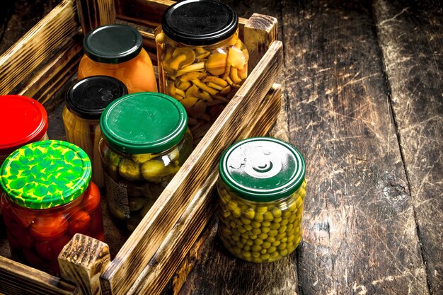 Photo conserve les champignons et les légumes dans une boîte. sur une table en bois.