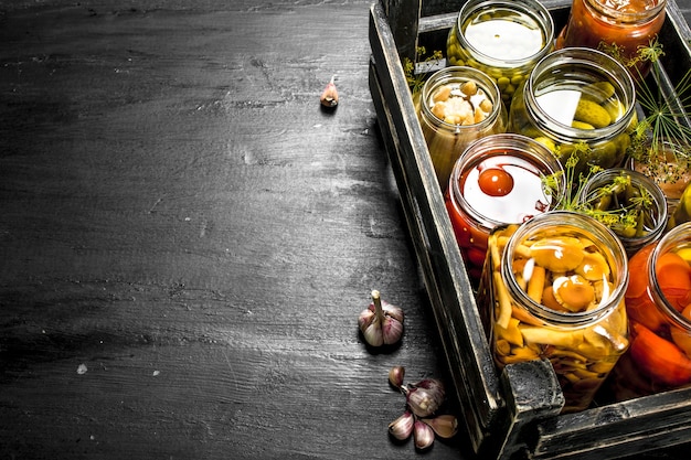 Conserve les légumes dans des bocaux en verre dans une vieille boîte. Sur le tableau noir.