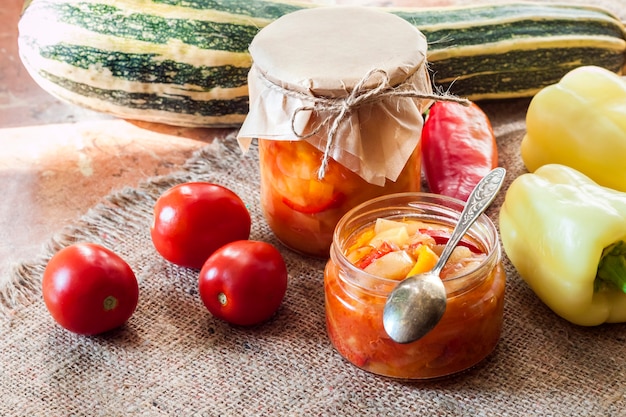 Photo conserve maison. salade de courgettes et poivrons dans un bocal en verre avec des ingrédients en arrière-plan