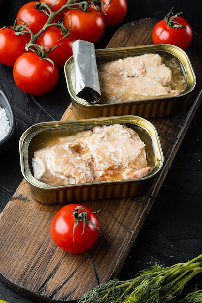 Photo conserves de saumon, conserves de poisson, ensemble sur planche à découper en bois, sur fond noir