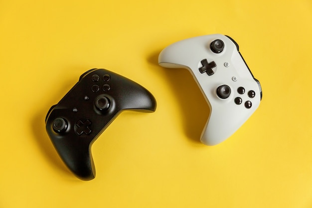 Console de jeu de manette de jeu deux joystick blanc et noir sur une surface de pin-up de mode moderne tendance jaune coloré. Concept de confrontation de contrôle de jeu vidéo de compétition de jeux informatiques. Symbole du cyberespace