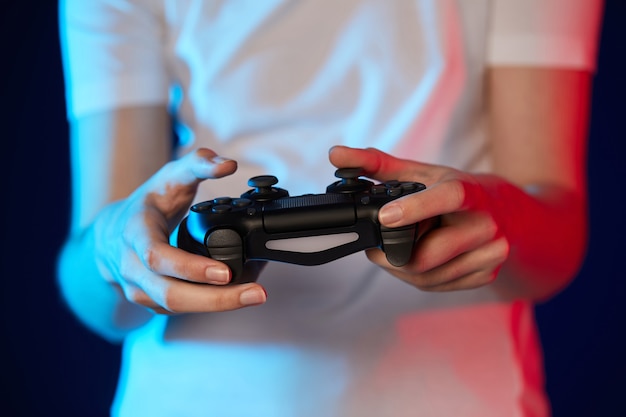 Console de jeux vidéo en mains féminines, gros plan. Éclairage au néon