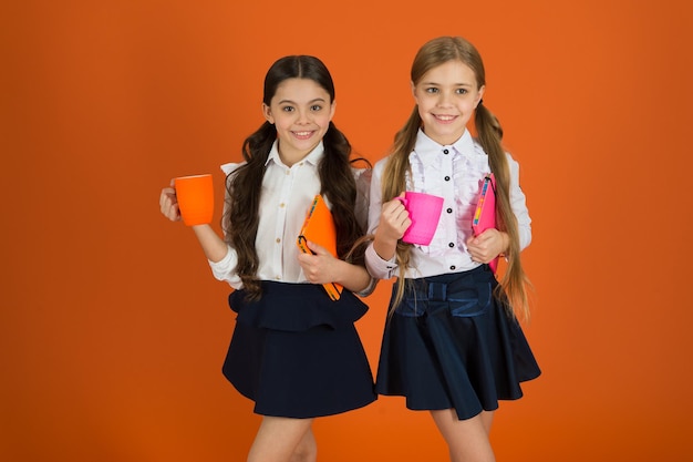 Consommation du petit-déjeuner Écoliers prenant leur petit-déjeuner le matin Petites filles appréciant leur petit-déjeuner à l'école Jolies écolières tenant des tasses et des livres Petits enfants buvant du thé ou du lait le matin