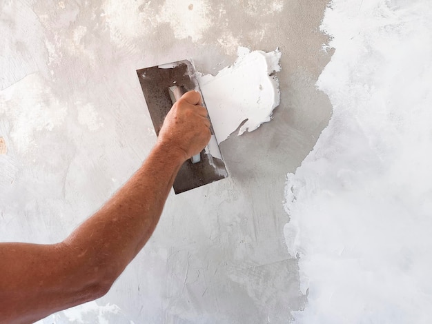 Constructeur à l'aide d'un outil de plâtrage pour la finition d'un vieux mur.