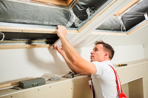 Le constructeur attache des planches de bois dans le grenier