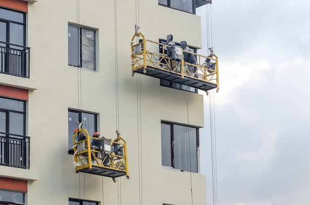 Constructeur Au Travail De Construction De Façade Berceaux Suspendus.