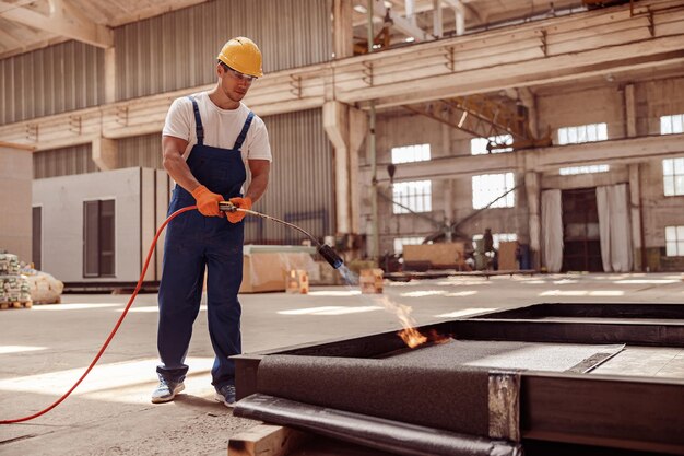 Constructeur de bel homme utilisant un brûleur à gaz sur un chantier de construction