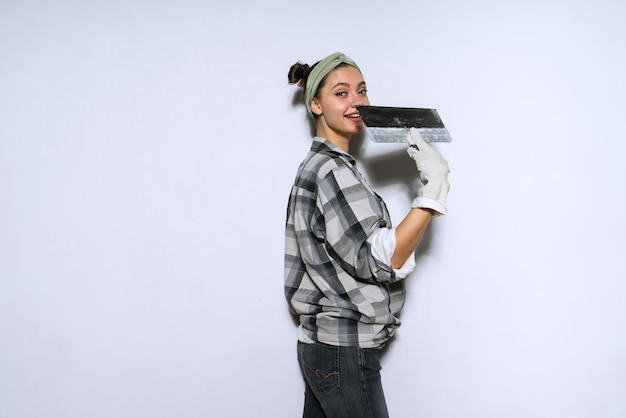Constructeur de belle jeune femme faisant des réparations, tenant une spatule dans les mains