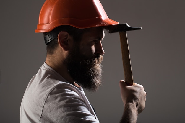 Constructeur en casque, marteau, bricoleur, constructeurs en casque. Homme barbu