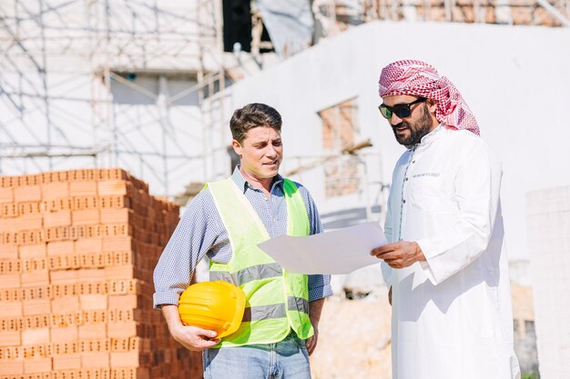 Constructeur de construction travaillant avec un homme arabe chef de projet investisseur immobilier pour un nouveau bâtiment