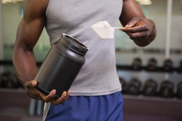 Constructeur de corps tenant une boule de mélange de protéines dans la salle de gym