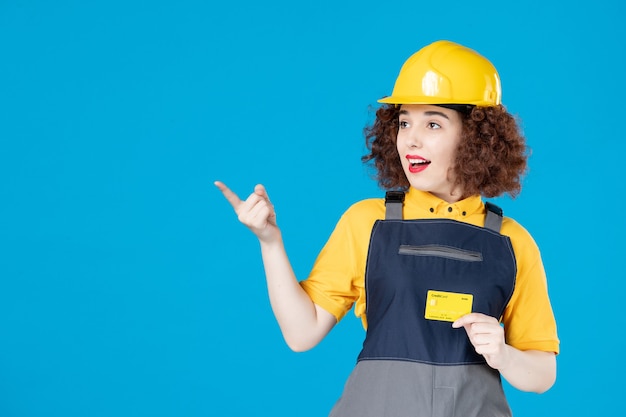 Constructeur féminin en uniforme avec carte de crédit sur un bleu