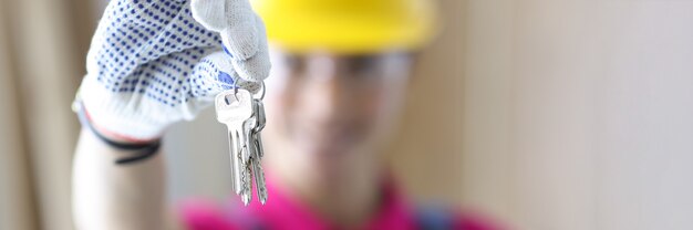 Constructeur de femme dans un casque de protection tenant des clés dans les mains en gros plan