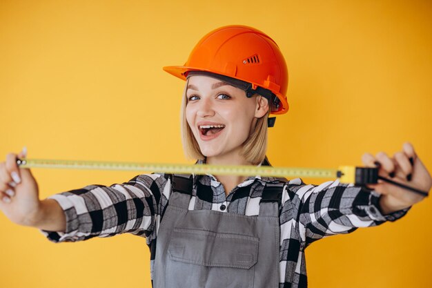 Photo constructeur de femme portant un casque et une salopette orange à l'aide de la roulette