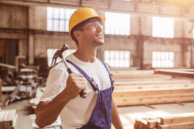 Constructeur gai avec le marteau travaillant au chantier de construction