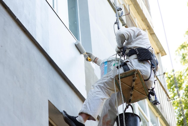 Le constructeur de grimpeur peint la façade du plan rapproché de bâtiment