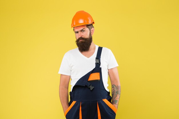 Constructeur d'homme brutal. Ingénieur constructeur en uniforme. Casque de chantier homme. Possibilité de rénover la maison pour rafraichir, agrandir et renouveler. L'artisan garde la tête en sécurité dans le casque. Amélioration et rénovation du bâtiment.