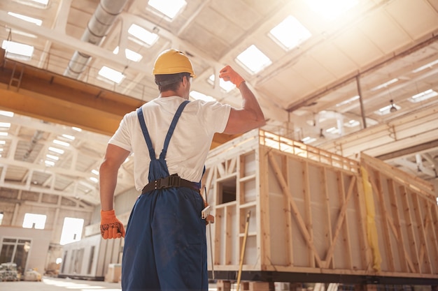 Constructeur masculin athlétique démontrant son bras musclé