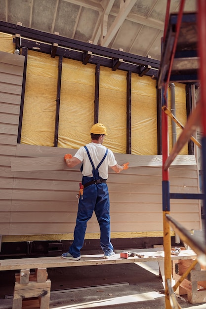 Constructeur masculin construisant une maison sur un chantier de construction