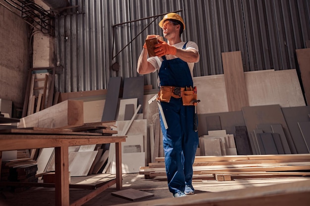 Constructeur masculin transportant une planche de bois de bois sur un chantier de construction