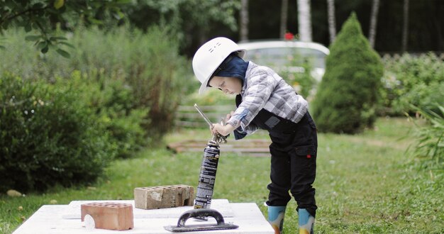 constructeur de petit garçon dans un casque blanc joue avec un cylindre de mousse de polyuréthane