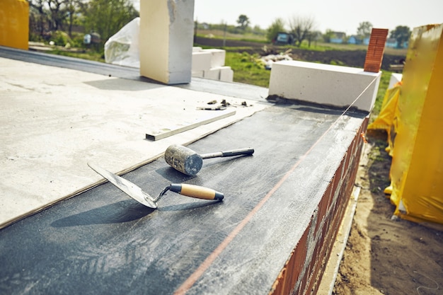 Le constructeur pose un bloc de béton cellulaire sur un chantier de construction