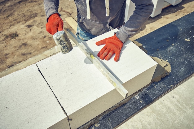 Le constructeur pose un bloc de béton cellulaire sur un chantier de construction