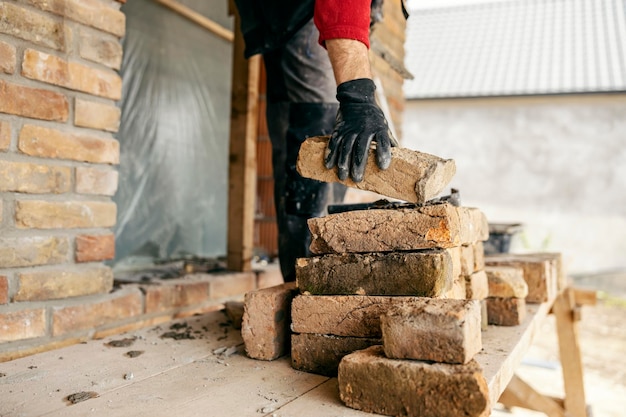 Un constructeur prend une brique d'un tas sur une zone de construction