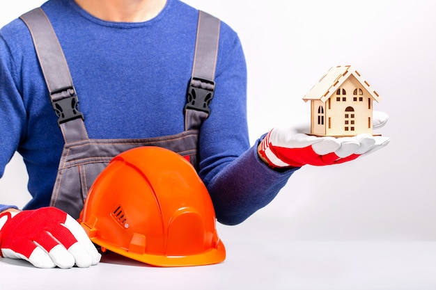 Constructeur en uniforme tenant une maquette de la maison.