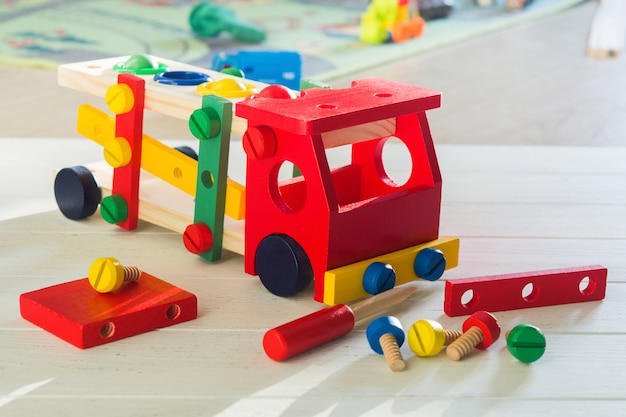 Constructeur de voiture en bois coloré pour les enfants. Concept d'éducation préscolaire avec de nombreux détails, tournevis et vis sur table en bois