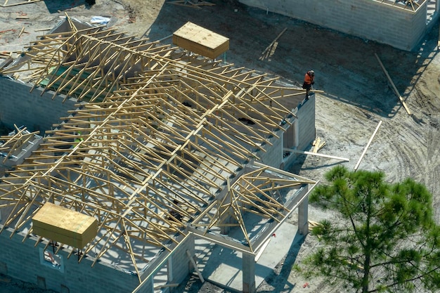 Constructeurs professionnels travaillant sur la construction du toit d'une maison de banlieue inachevée avec structure à ossature en bois dans la zone rurale de Floride Concept de développement de logements en Amérique