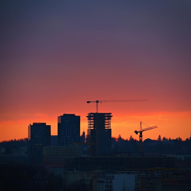 Photo construction de bâtiments avec des grutiers et des machines de construction au coucher du soleil concept pour la construction et l'industrie