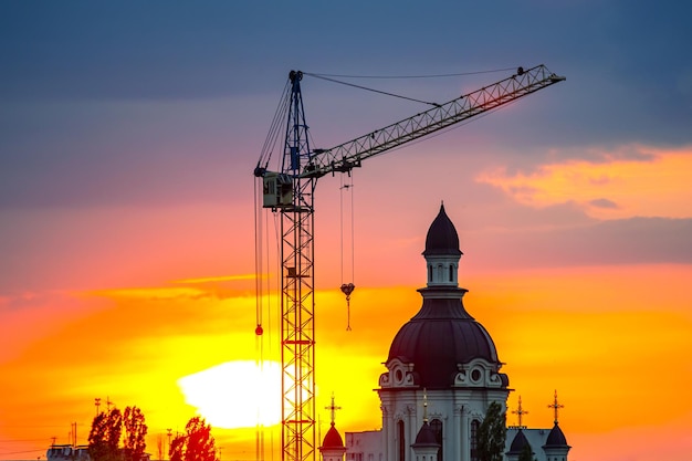 Photo construction d'une église chrétienne à l'aide d'une grue de construction sur un fond de coucher de soleil