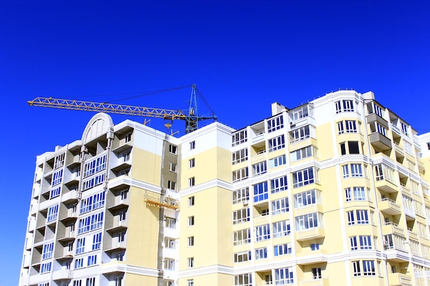 construction d'une maison moderne à plusieurs étages avec grue de levage sur fond de ciel bleu