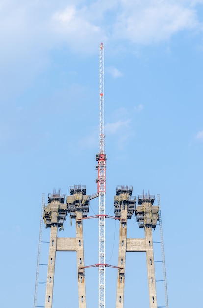 La construction d'un pont sur la rivière avec les supports, les éléments structurels, les grues