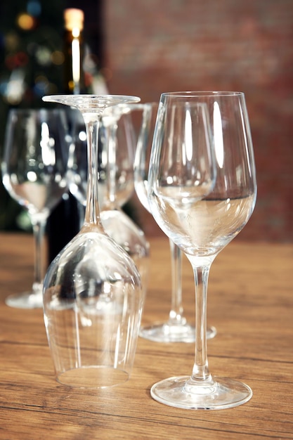 Construction de verres à vin vides et bouteille sur table en bois sur fond flou