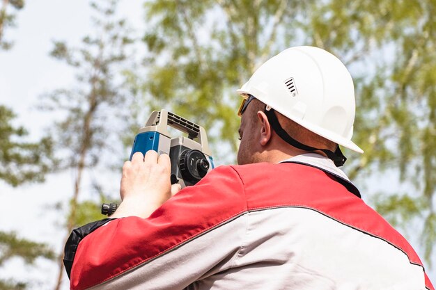 Construction d'une zone résidentielle Implantation géodésique Arpenteur sur un grand chantier de construction Un homme avec un tachymètre pendant le travail Makshader