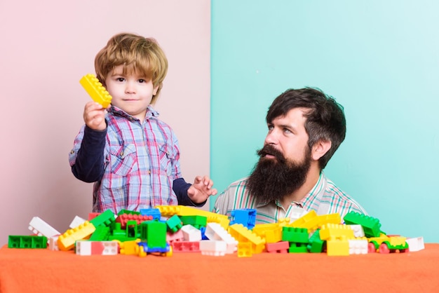 Construire une maison avec un constructeur famille heureuse loisirs père et fils jouent au jeu développement de l'enfant petit garçon avec un homme barbu papa jouant ensemble construire une maison ensemble construire une maison