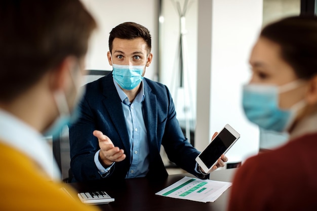 Consultant financier parlant aux clients tout en utilisant une tablette numérique lors d'une réunion