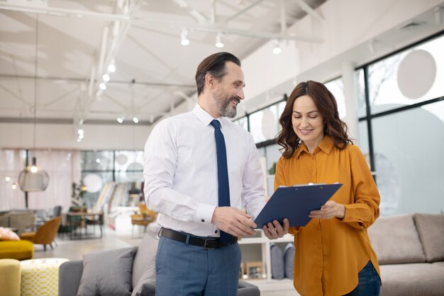 Consultant en magasin de meubles montrant la liste de prix au nouveau client