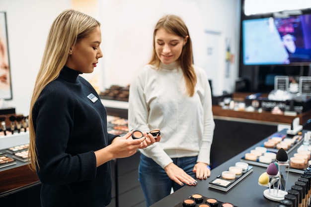 Un consultant montre de la poudre à une femme dans un magasin de maquillage